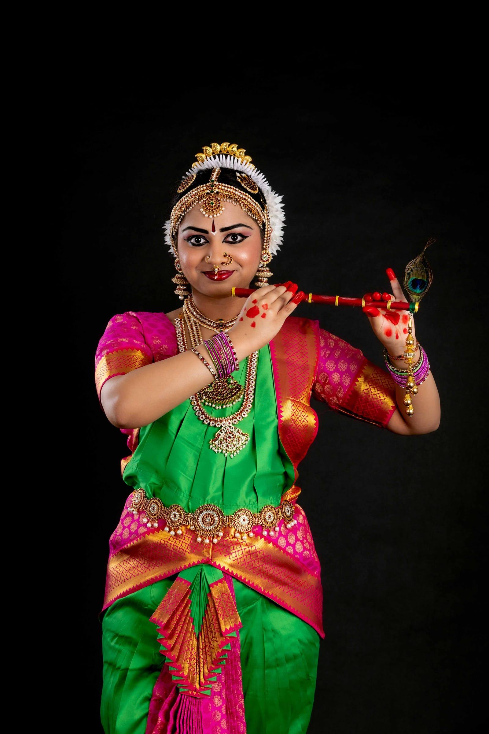 Bharatanatyam dancer holding a flute in costume, arangetram portrait
