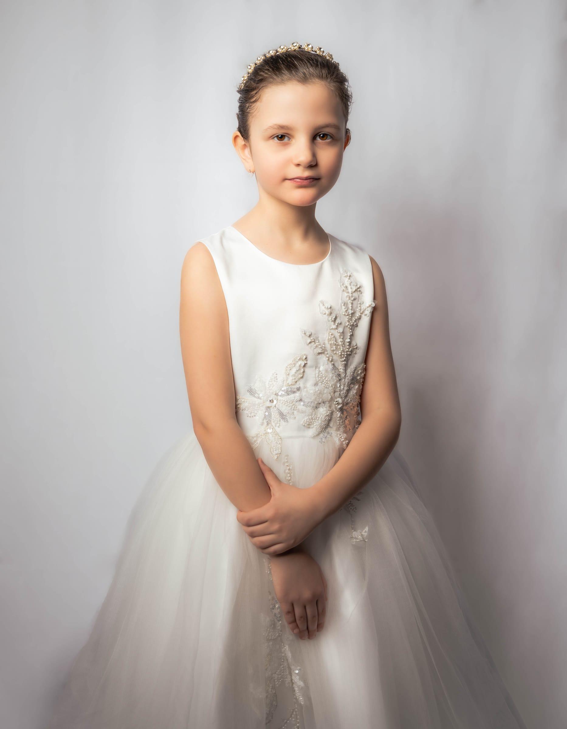 First holy communion portrait of a girl in a white dress and tiara
