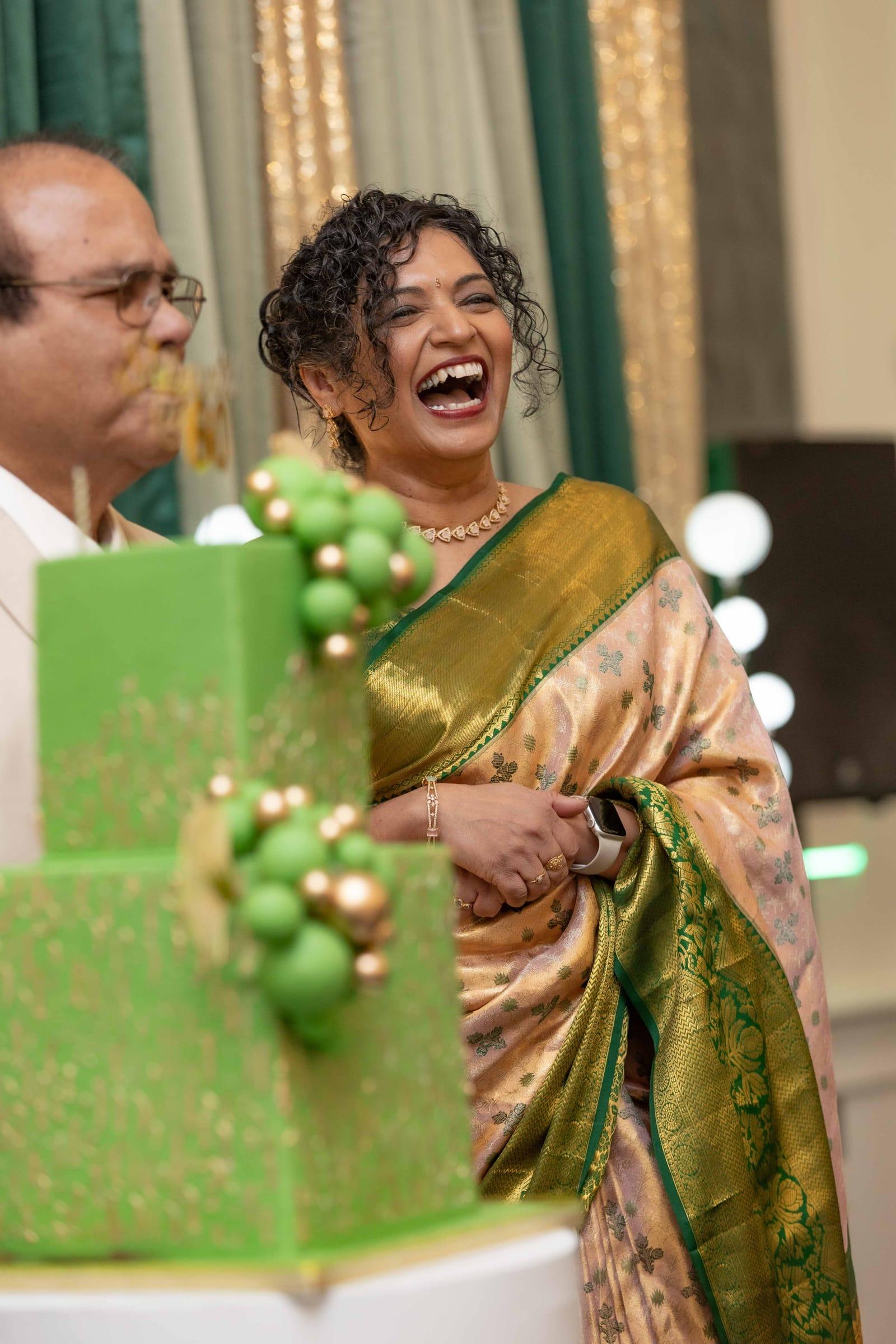 Laughing guest of honour cutting a cake at a milestone birthday