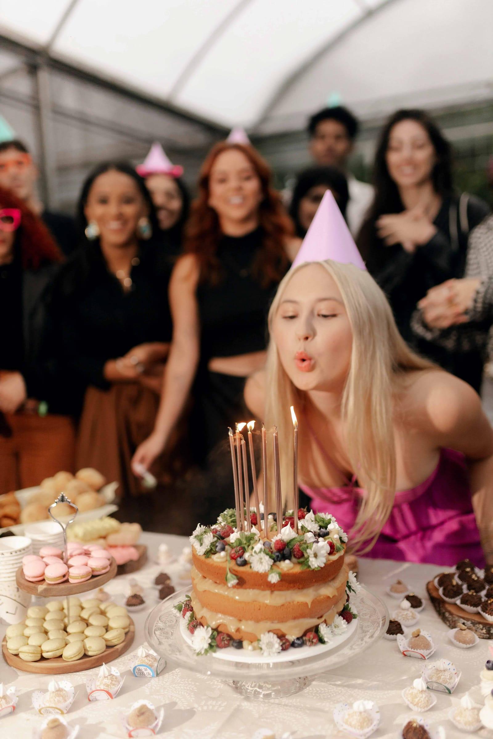 Woman blows out birthday candles surrounded by friends at a party