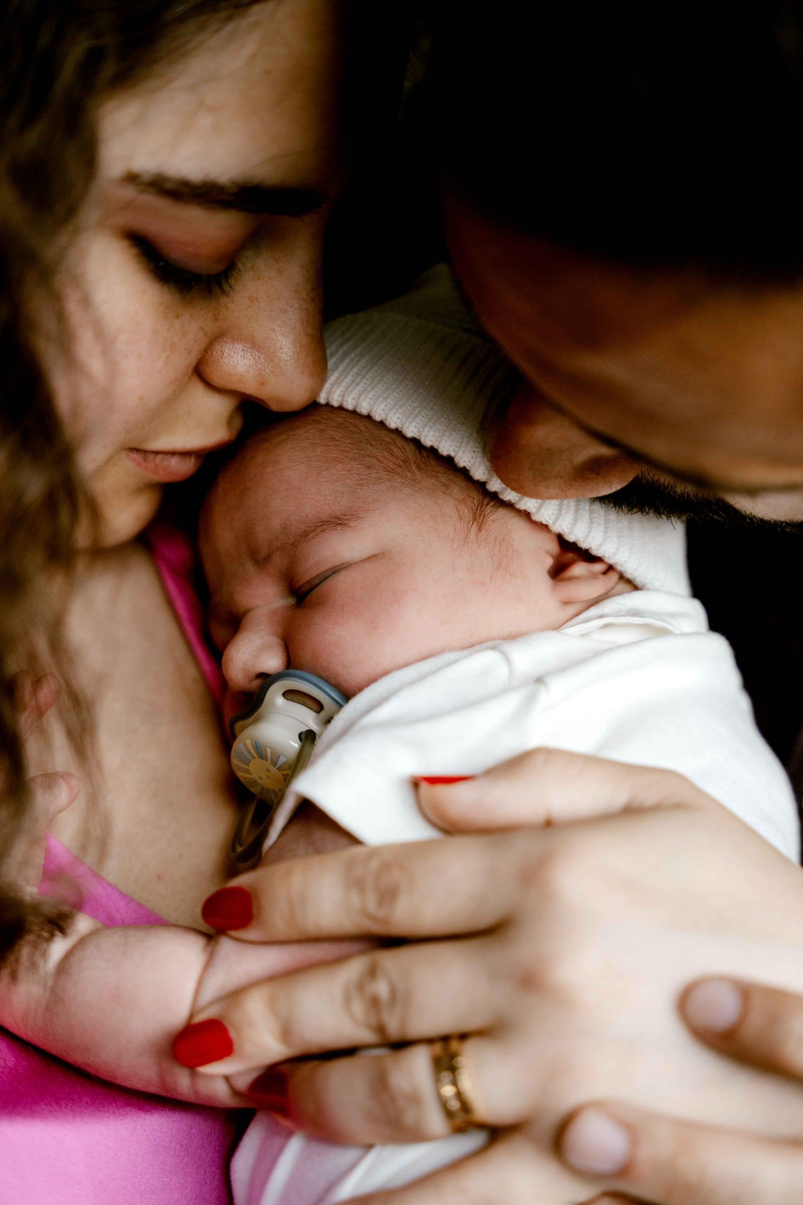 Mother cradles her sleeping newborn, tender newborn photography