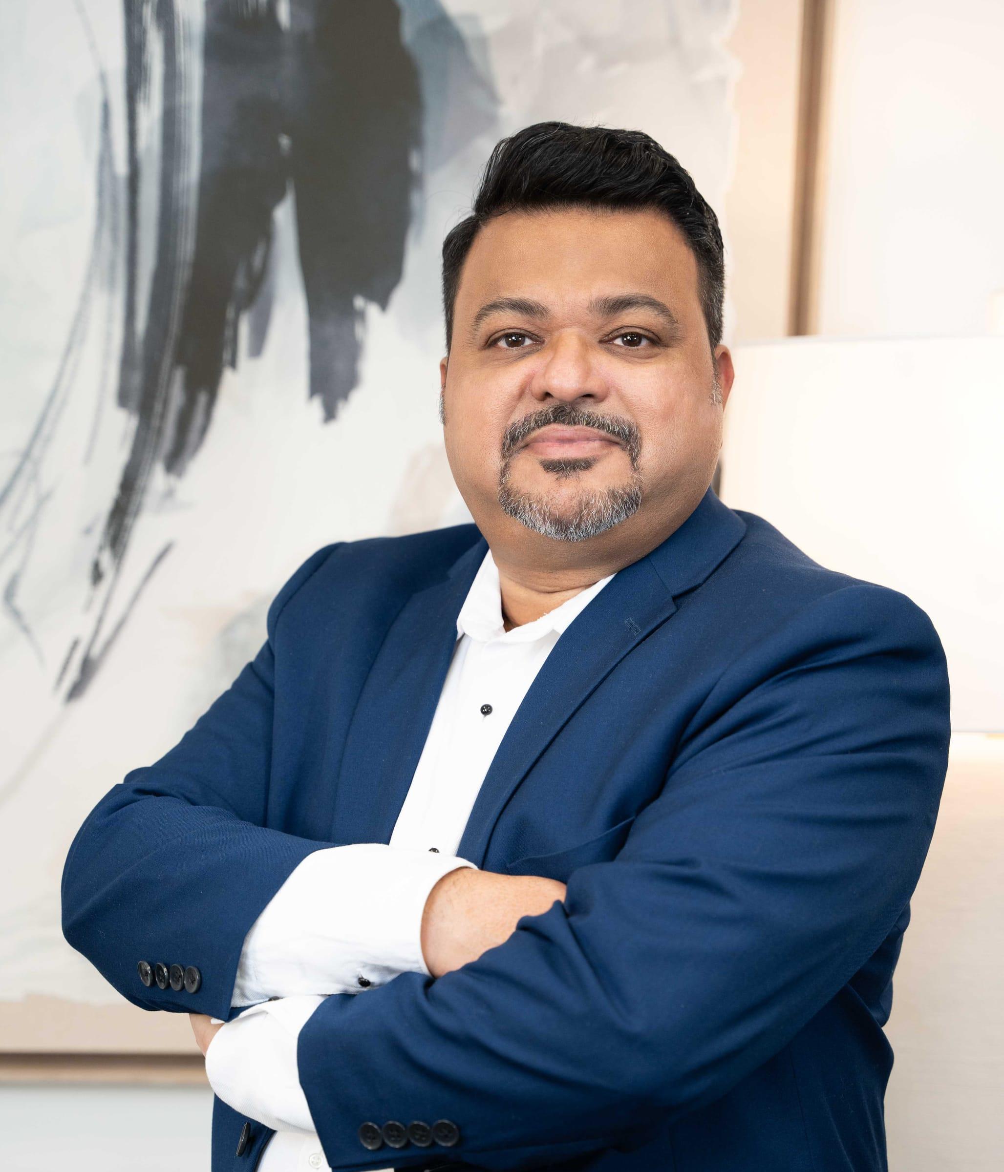 Man in a navy blazer with arms crossed in an editorial portrait