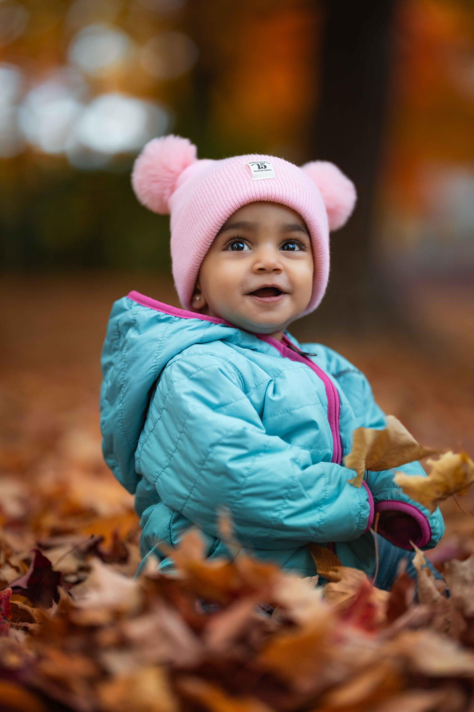 Smiling baby in a teal jacket in autumn leaves, Toronto fall mini session