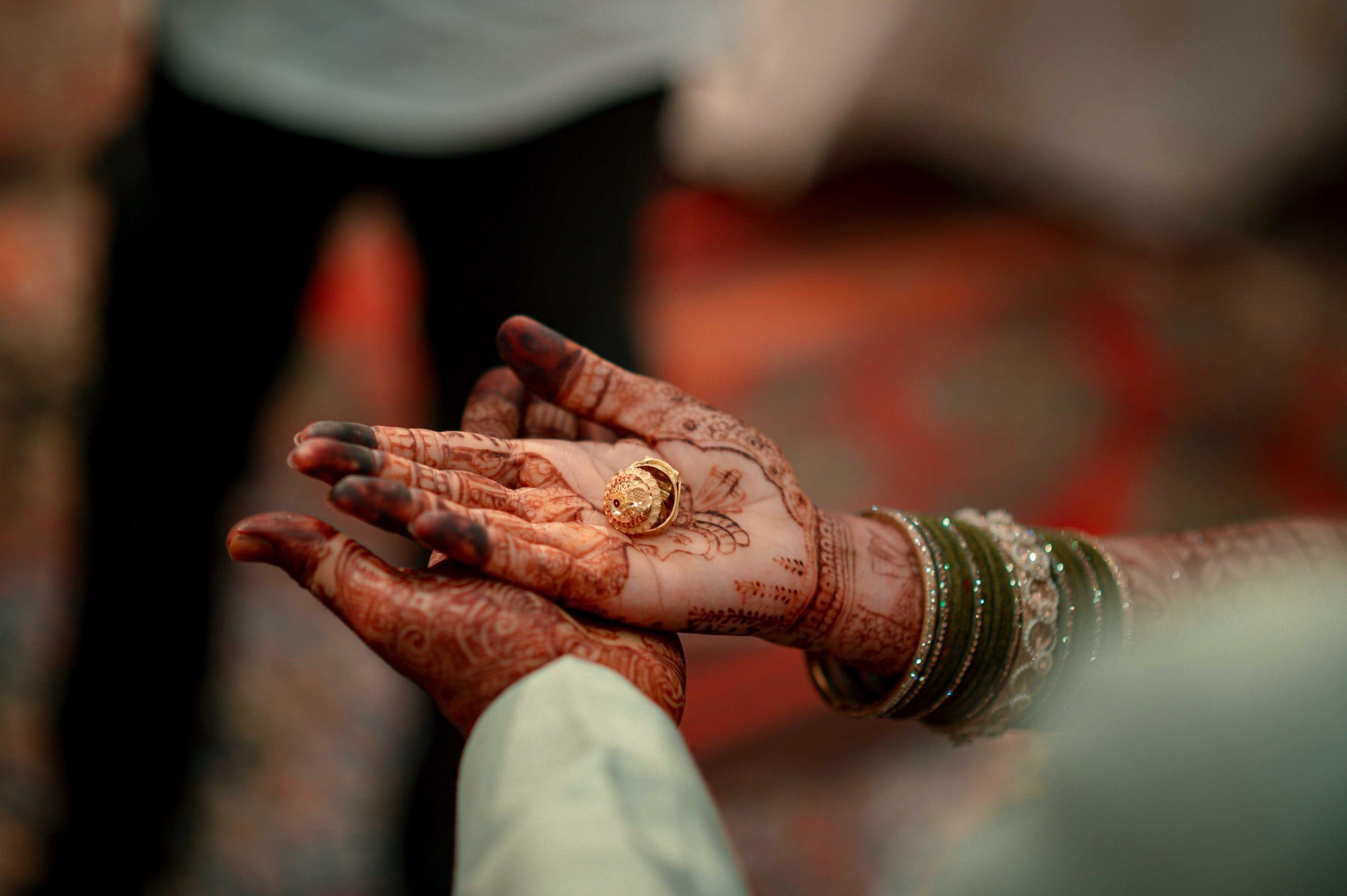 Bride's henna-covered hands holding her ring, mehndi detail