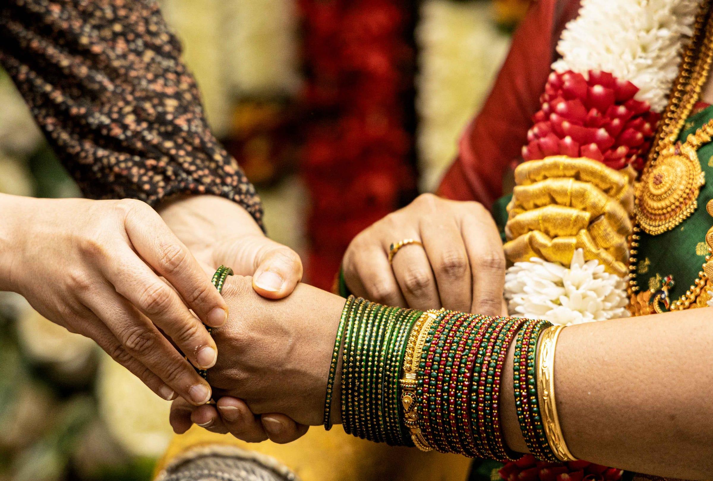 Hands joined during a traditional Hindu wedding ritual with gold bangles