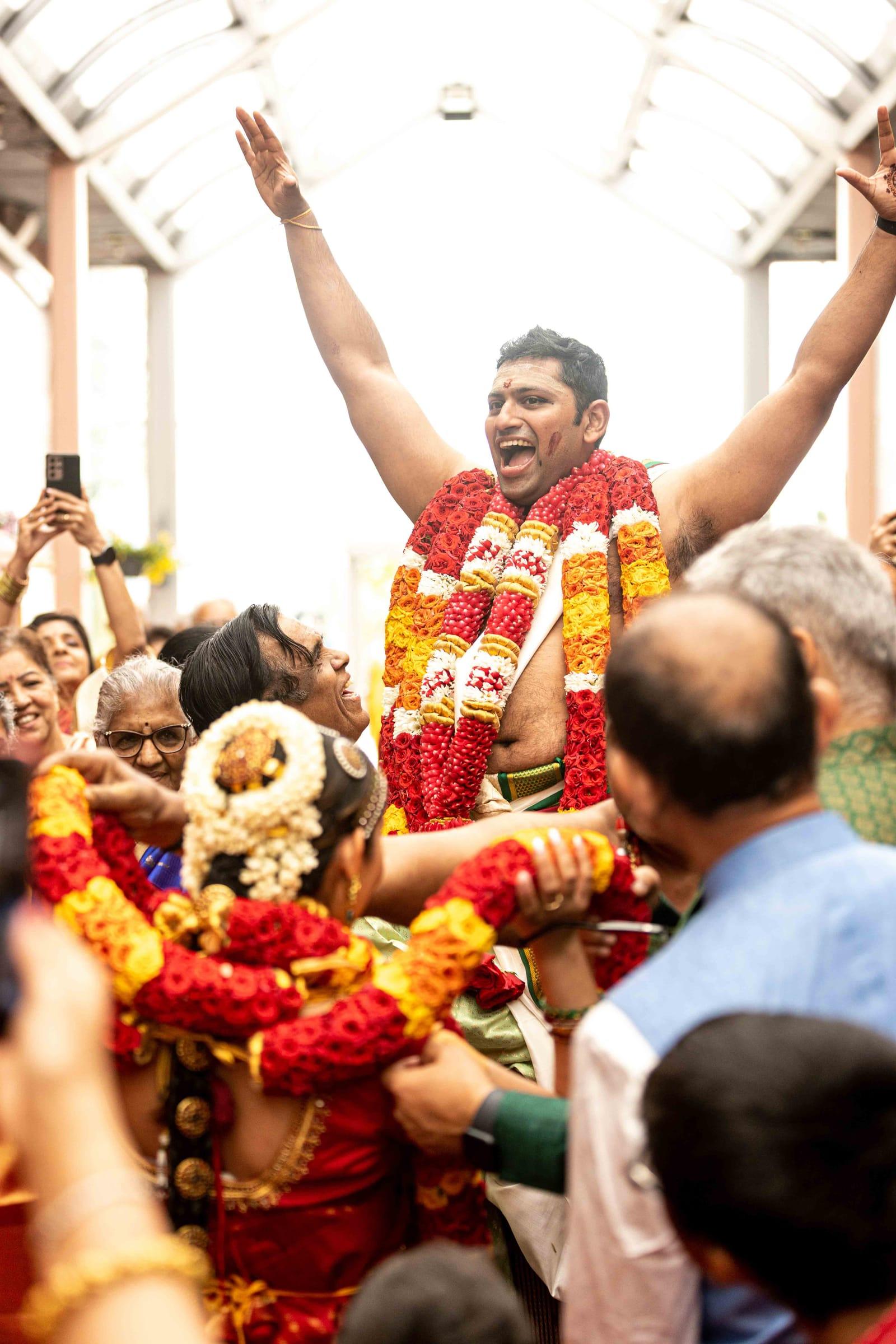 Groom lifted by celebrating guests during a wedding baraat