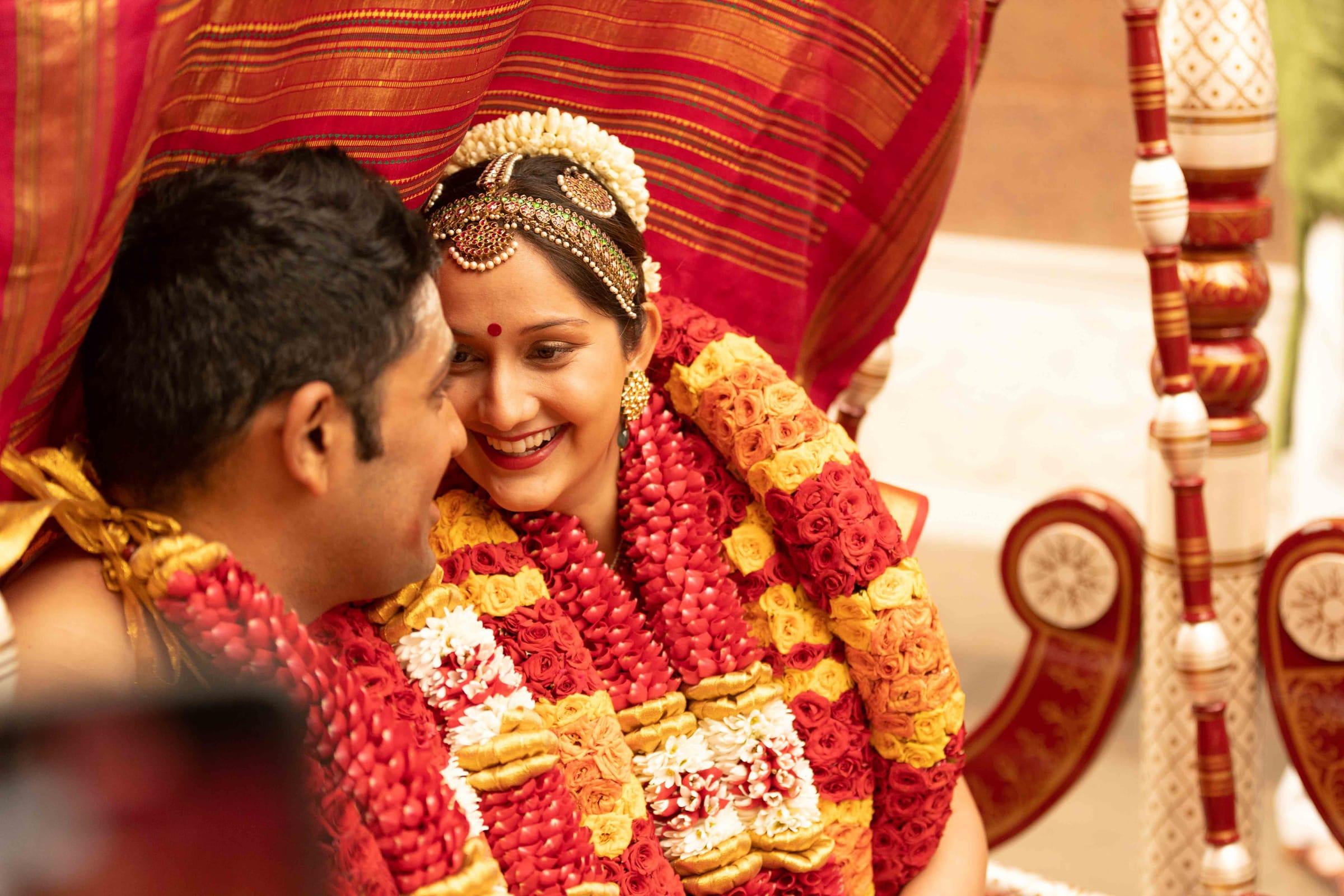 Bride and groom share a candid smile at the mandap
