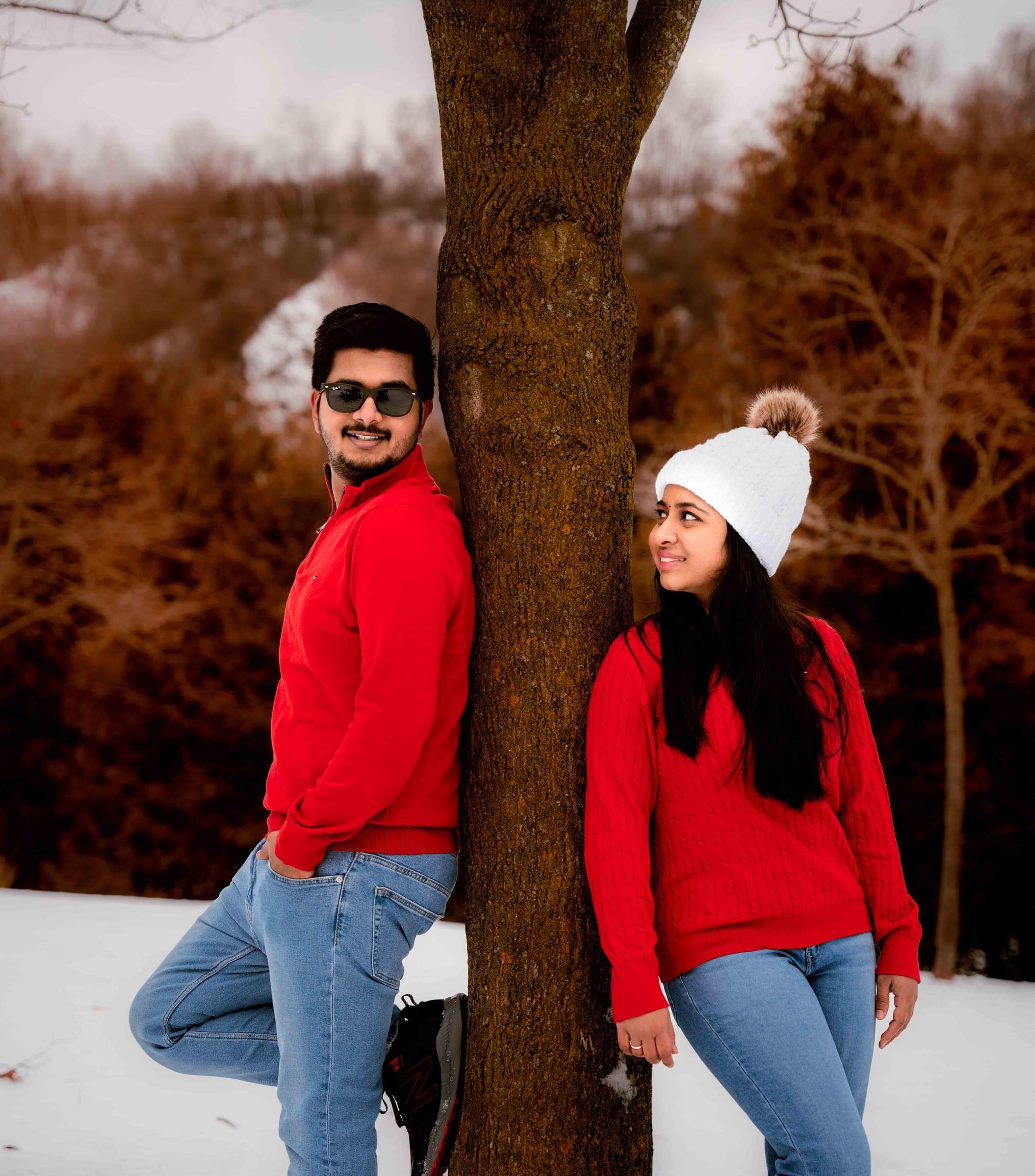 Couple in matching red sweaters during a snowy winter engagement shoot