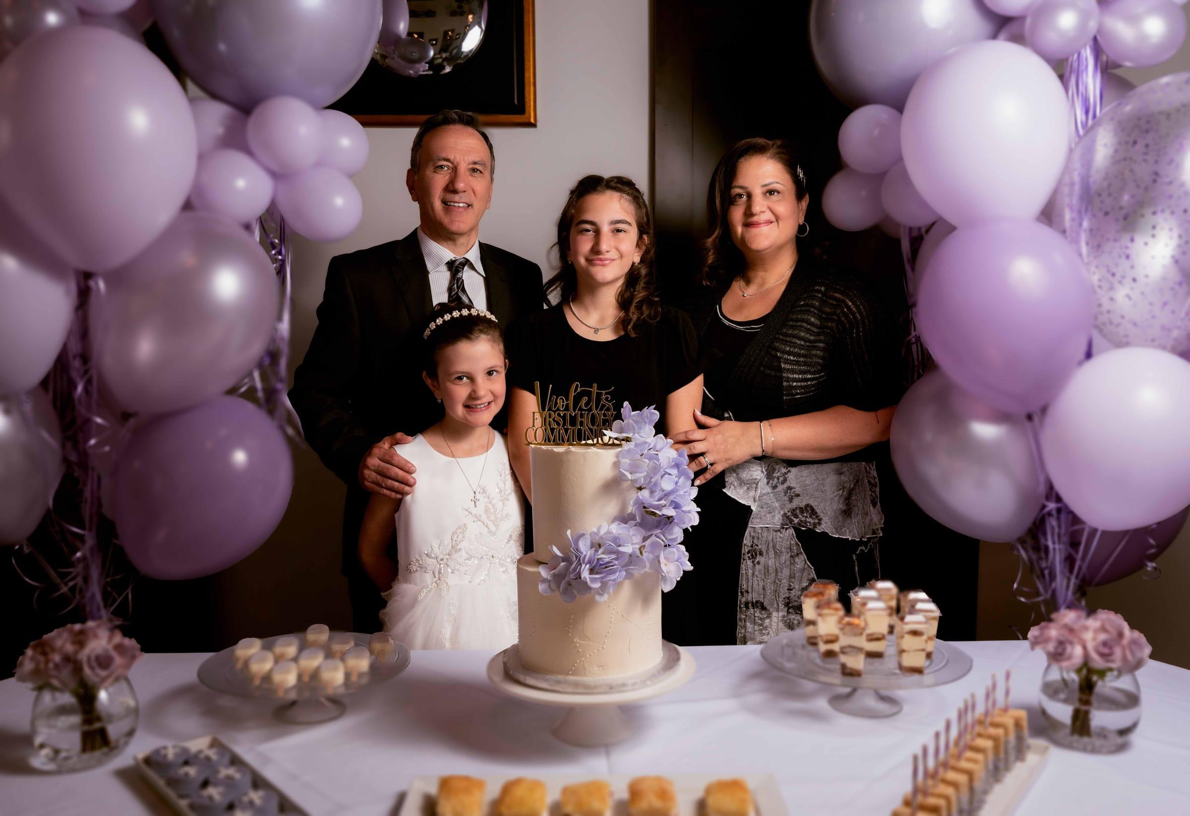 Family celebrates a first holy communion with a cake and balloons