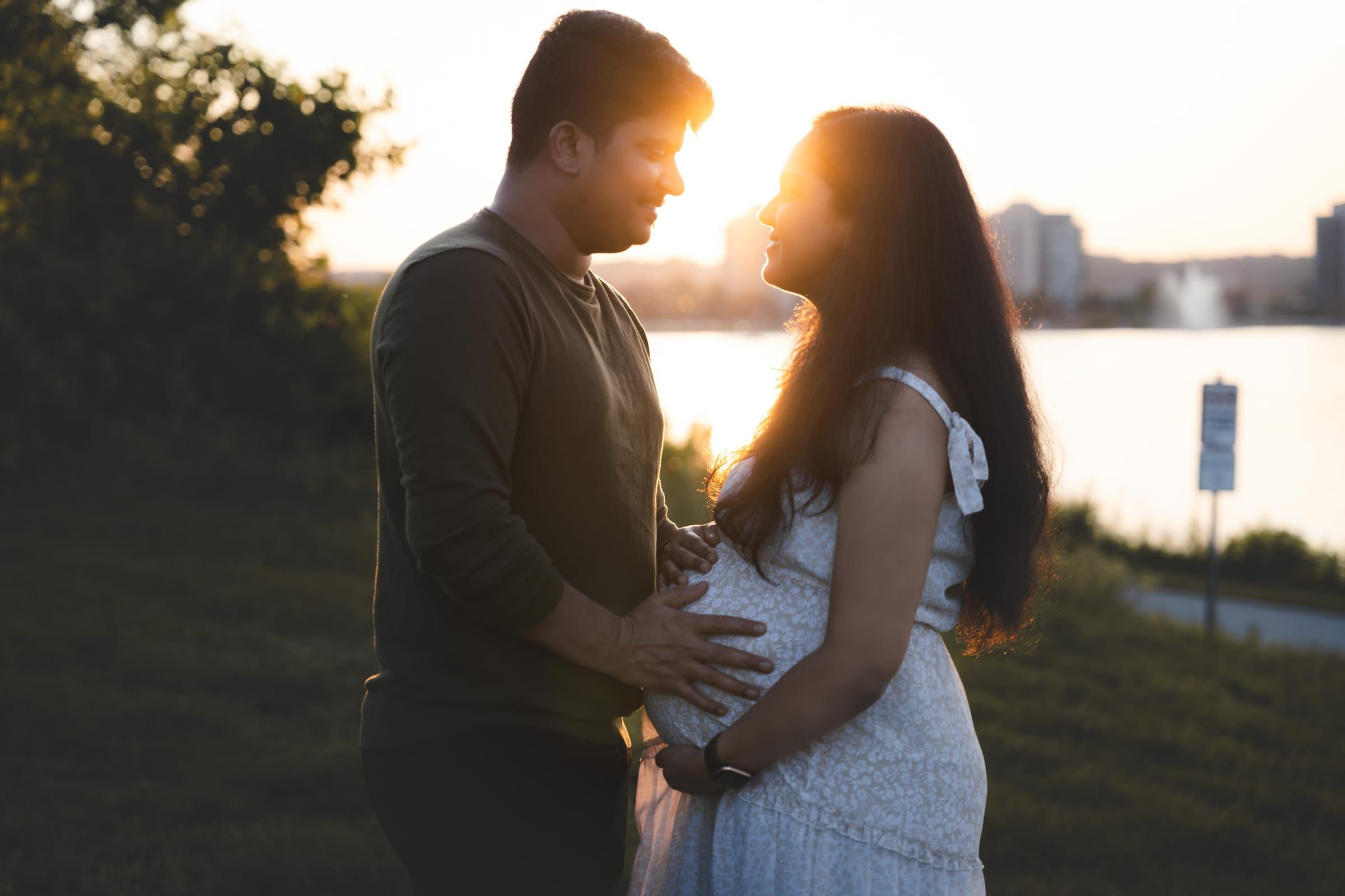 Expecting couple silhouetted by the sunset by the lake, maternity session