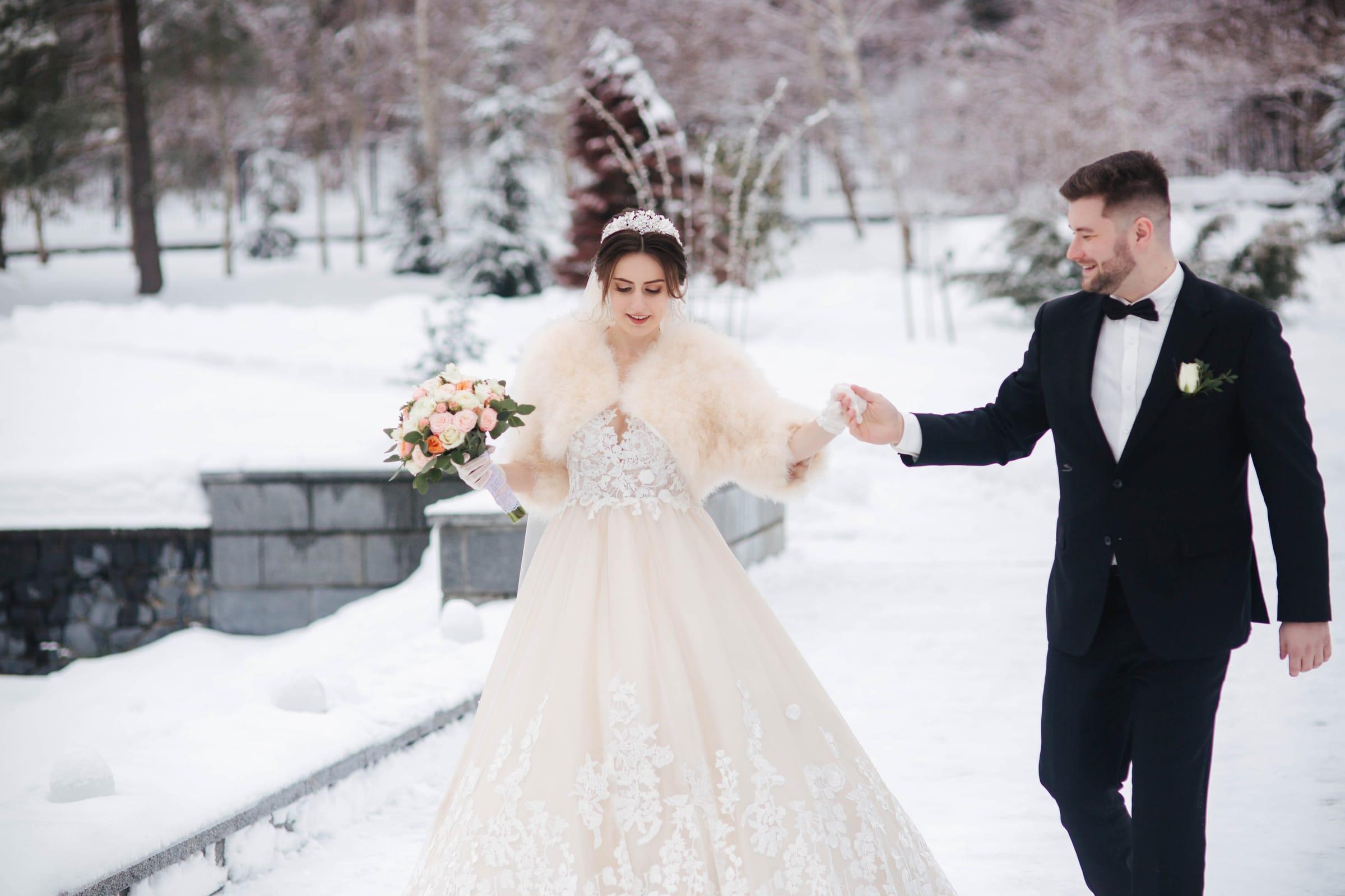 Groom leads his bride through fresh snow on their winter wedding day in the GTA